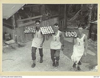 JACQUINOT BAY, NEW BRITAIN. 1945-04-26. 4 FIELD AMBULANCE MEMBERS WHO ATTENDED A SCHOOL OF COOKING CONDUCTED BY WARRANT OFFICER II GIBBES, CARRYING AWAY FINISHED ARTICLES FROM THE KITCHEN. ..