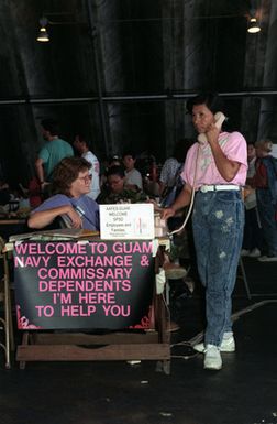 A woman makes a telephone call from a desk in a temporary evacuation center during Operation Fiery Vigil. The center was set up to process military dependents who were evacuated from the Philippines after volcanic ash from the eruption of Mount Pinatubo disrupted operations at Clark Air Base and Naval Station, Subic Bay.