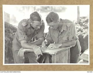 DONADABU AREA, NEW GUINEA. 1943-12-01. VX15739 LIEUTENANT W. V. HORTON (LEFT) AND VX18707 GUNNER C. WILSON (RIGHT), BOTH OF THE 2/4TH AUSTRALIAN FIELD REGIMENT PLOTTING SHELL BURSTS DURING AN ..