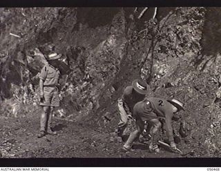 REINHOLD HIGHWAY, NEW GUINEA, 1943-08-24. TROOPS OF HEADQUARTERS, ROYAL AUSTRALIAN ENGINEERS, 11TH AUSTRALIAN DIVISION, CLEARING AWAY A SMALL LANDSLIDE NEAR THE 9 MILE POINT. LEFT TO RIGHT: ..