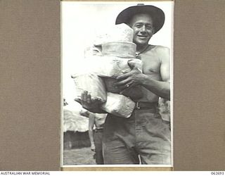 RAMU VALLEY, NEW GUINEA. 1943-12-22. VX13083 PRIVATE F. CORTEZ OF THE 2/31ST AUSTRALIA INFANTRY BATTALION LOADED WITH CHRISTMAS PARCELS FOR HIS MATES AFTER COLLECTING THEM FROM THE 7TH AUSTRALIAN ..