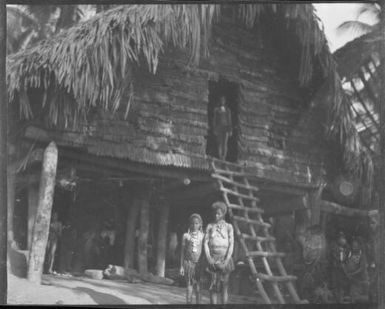 Two people standing beside a house ladder, Tambunum, Sepik River, New Guinea, 1935 / Sarah Chinnery