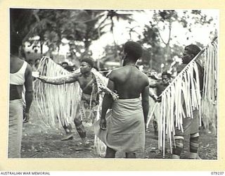 MANGUNUI, JACQUINOT BAY, NEW BRITAIN. 1945-02-25. NATIVES PERFORMING ONE OF THEIR TRIBAL DANCES DURING A SING- SING AT THE AUSTRALIAN NEW GUINEA ADMINISTRATIVE UNIT NATIVE COMPOUND