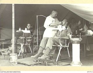 LAE, NEW GUINEA, 1944-03-25. NX70931 MAJOR A. A. FRIZELLE (1), GIVING DENTAL TREATMENT TO PRIVATE H. H. BROWN, 2/12TH INFANTRY BATTALION (3), AT THE 112TH CONVALESCENT DEPOT. IN THE BACKGROUND IS ..