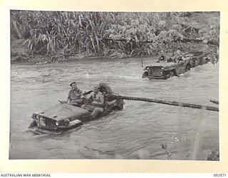 BOUGAINVILLE. 1945-05-23. JEEPS AND TRAILERS CROSSING THE POROREI RIVER, TAKING SPARE PARTS FOR REPAIR WORK ON A MATILDA TANK OF B SQUADRON, 2/4 ARMOURED REGIMENT, WHICH HAD A MECHANICAL BREAKDOWN ..