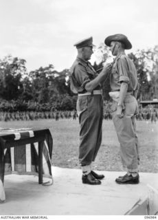 TOROKINA, BOUGAINVILLE. 1945-09-24. MAJOR GENERAL W. BRIDGEFORD GENERAL OFFICER COMMANDING 3 DIVISION, PRESENTING CAPTAIN W.H. SCOTT WITH THE MILITARY CROSS DURING PRESENTATION OF AWARDS AND MARCH ..
