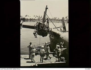 MADANG, NEW GUINEA. 1945-01-15. THE STARBOARD ENGINE OF A MARTIN MARINER FLYING BOAT AIRCRAFT, A70-8 VHCPH, OF NO. 41 SQUADRON RAAF, IS CHANGED ALONGSIDE A JETTY. FITTINGS ARE PROVIDED ON THE WING ..