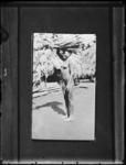 Woman standing, balancing goods on head.