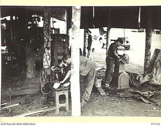 LAE, NEW GUINEA. 1944-03-24. THE GENERAL ENGINEERING SHOP AT THE 2/125TH BRIGADE WORKSHOP ATTACHED TO THE 7TH DIVISION. THESE TEMPORARY SHELTERS ARE A NECESSITY IN THE EXCESSIVE HEAT AND RAIN. ..