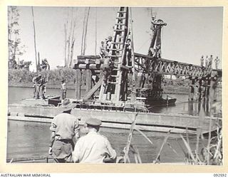 SOUTH BOUGAINVILLE. 1945-05-27. MEMBERS OF 11 FIELD COMPANY ROYAL AUSTRALIAN ENGINEERS, CONSTRUCTING SAVIGE BRIDGE OVER THE JABA NO. 1 RIVER. PILE DRIVING FRAMES MOUNTED ON PONTOON RAFTS ARE AT ..