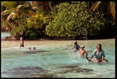 Group of men and boys swimming in lagoon, Cook Islands