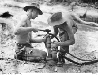 JACQUINOT BAY, NEW BRITAIN. 1944-12-11. SAPPER W. TESTER (1) AND SAPPER D'ARCY (2) OF THE 13TH FIELD COMPANY, CONNECTING UP A COMPRESSED AIR SUMP PUMP DURING THE BUILDING OF A NEW BRIDGE ACROSS A ..