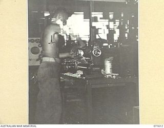 LAE, NEW GUINEA. 1944-03-24. VX80546 CRAFTSMAN R. J. CHINNOCK, TURNING INSTRUMENT PARTS ON A 4 INCH LATHE AT THE AUSTRALIAN FORTRESS WORKSHOP