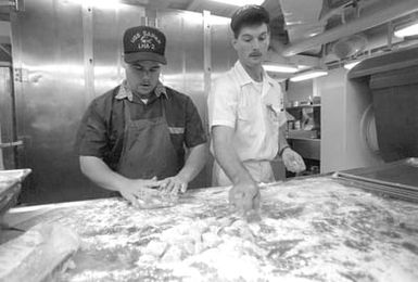 Two mess management specialists aboard the amphibious assault ship USS SAIPAN (LHA-2) make cookies in preparation for the arrival of evacuees from the U.S. Embassy in Monrovia, Liberia. The SAIPAN is on station off the coast of Liberia for OPERATION SHARP EDGE