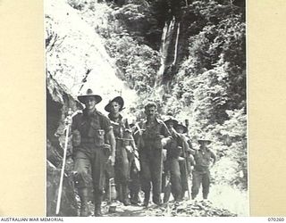 FARIA VALLEY, NEW GUINEA, 1944-02-09. 2/10TH INFANTRY BATTALION MEMBERS MOVING ALONG A TRACK CUT IN ROCK BY THE ENGINEERS