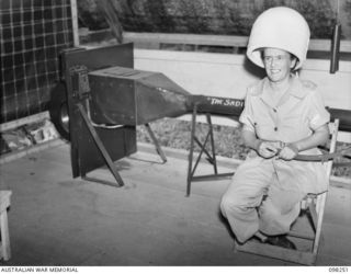 LAE, NEW GUINEA. 1945-10-10. LIEUTENANT S.H. BUDGE, AMENITIES OFFICER, AUSTRALIAN WOMEN'S ARMY SERVICE BARRACKS, UNDER A HAIR DRYER CONSTRUCTED BY LAE BASE WORKSHOPS