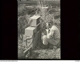 AITAPE, NORTH EAST NEW GUINEA. 1944-04-24. CORPORAL H. CLEMENTS, LILYDALE, VIC, RAAF WIRELESS MECHANIC, USES A FIELD RADIO TO CALL THE FIRST ALLIED AIRCRAFT TO MAKE A LANDING APPROACH TO TADJI ..