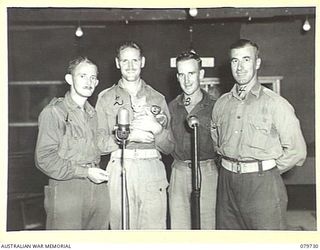 BOSLEY FIELD, BOUGAINVILLE, SOLOMON ISLANDS. 1945-03-15. STAFF OF THE AUSTRALIAN ARMY BROADCASTING STATION IN THE AUDITORIUM. IDENTIFIED PERSONNEL ARE:- QX37392 SERGEANT GARFIELD WILLIAM MADDERS OF ..
