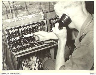 MOTUPINA POINT, BOUGAINVILLE ISLAND. 1945-01-19. VX87764 GUNNER A.G. IMPEY, 2ND FIELD REGIMENT, OPERATING THE SWITCHBOARDS OF NO. 5 BATTERY, WHICH ARE A 6 AND 10 PLUG AND CARRY THE LINES FROM ..