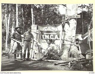 AN ADVANCED Y.M.C.A. POST JUST BEHIND THE FORWARD LINES IN THE NEW GUINEA JUNGLE. THE VALUE OF THESE UNPRETENTIOUS OUTPOSTS IS INESTIMABLE AND THE WORK OF THE MEN WHO MAINTAIN CANNOT BE TOO HIGHLY ..