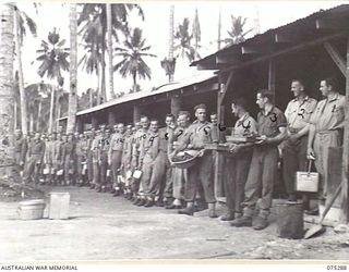 MADANG, NEW GUINEA. 1944-08-15. PERSONNEL OF THE 165TH GENERAL TRANSPORT COMPANY LINED UP AT THE UNIT MESS HUT FOR THEIR EVENING MEAL. IDENTIFIED PERSONNEL ARE:- NX125238 PRIVATE T.B. BELL (1); ..