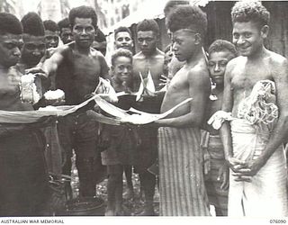 KARKAR ISLAND, NEW GUINEA. 1944-09-19. ISLAND NATIVES WORKING UNDER THE DIRECTION OF THE AUSTRALIAN NEW GUINEA ADMINISTRATIVE UNIT BEING ISSUED WITH RICE BEFORE MOVING TO ALLOTTED WORK AT ..