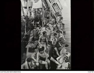 MILNE BAY, PAPUA. C.1944-02. AIRMEN OF NO. 75 SQUADRON RAAF LINING THE SIDE OF THE SHIP TO WATCH SWIMMERS (OUT OF SIGHT) HAVING A RACE ALONGSIDE THE SHIP