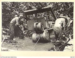 BOUGAINVILLE, SOLOMON ISLANDS. 1944-12-08. 5 AND 11 FIELD COMPANY, ROYAL AUSTRALIAN ENGINEERS SAPPERS ATTEMPTING TO DIG A BOGGED BULLDOZER FROM THE MUD. IDENTIFIED PERSONNEL ARE:- LANCE CORPORAL F. ..