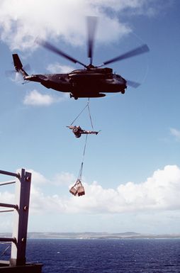 A CH-53 Sea Stallion helicopter prepares to lift a howitzer from the amphibious assault ship USS SAIPAN (LHA-2) during Fleet Ex 1-90