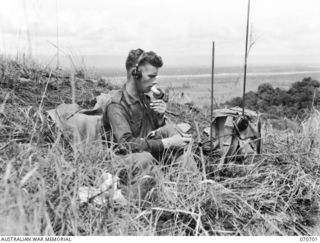 RAMU VALLEY, NEW GUINEA, 1944-02-29. VX67664 GUNNER K.W. LAWTHER, OF THE 12TH BATTERY, 4TH FIELD REGIMENT, RELAYING MESSAGES BY WIRELESS DURING A REGISTRATION SHOOT AT KESAWAI