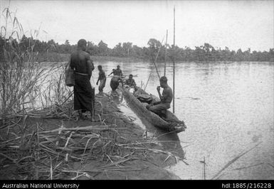 Eight men landing a canoe