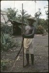 Portrait of man holding long rod and machete