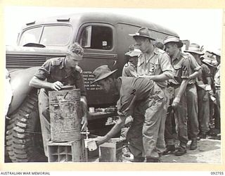 WEWAK AREA, NEW GUINEA. 1945-05-30. SERGEANT F.G. JENKINS (2), BEING SERVED WITH SOFT DRINK FROM SALVATION ARMY SENIOR REPRESENTATIVE V.G. WILSON (1), ON THE BEACH SOON AFTER COMING ASHORE FROM THE ..