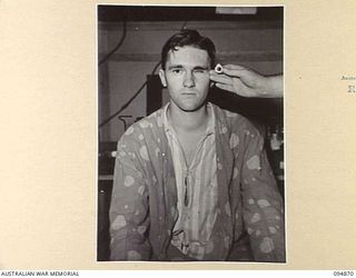 LAE AREA, NEW GUINEA. 1945-08-11. LIEUTENANT G.M. DOWNING BEING FITTED WITH AN ARTIFICIAL EYE AT 2/7 GENERAL HOSPITAL