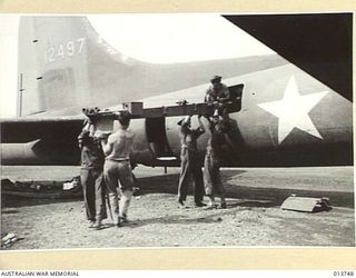 1942-12-07. NEW GUINEA. A 105MM M-3A1 HOWITZER COMPLETE WITH SPARES, TRACTOR AND AMMUNITION IS UNLOADED SOMEWHERE IN THE BATTLE AREA. THE GUN CREW ALSO CAME WITH THE GUN. PICTURE SHOWS A PORTION OF ..