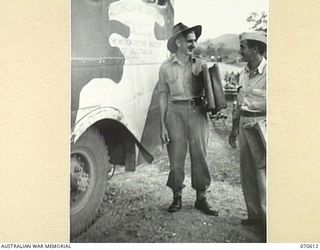 PORT MORESBY, PAPUA, 1944-02-25. AN AUSTRALIAN SOLDIER AND AN AMERICAN SERVICEMAN ARRIVING WITH PORTABLE SEATS AT A FIELD CINEMA. THE PICTURES ARE SHOWN AT HEADQUARTERS, NEW GUINEA FORCE BY THE ..