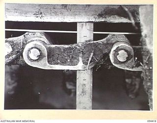TOROKINA AREA, BOUGAINVILLE. 1945-07-28. MEASURING THE SAG ON THE TRACK OF AN M24 GENERAL CHAFFEE LIGHT TANK AFTER NEGOTIATING DENSE JUNGLE FOR 70 MINUTES DURING TESTS CONDUCTED FOR THE WAR OFFICE
