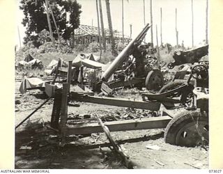 ALEXISHAFEN, NEW GUINEA. 1944-04-27. JAPANESE 77MM FIELD ANTI-AIRCRAFT GUNS NEAR THE WATERFRONT AMONG BUILDINGS THAT INDICATE THE RESULTS OF ALLIED BOMBING