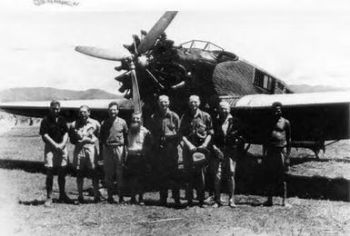 Mount Hagen aerodrome, Christmas 1934, picturing a Junkers aircraft with, in line from left, Dan Leahy, pilot,  Lord Sempill, Father Ross, Fox, Fox and Heydon / [A.J. Bearup]