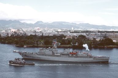 With the large harbor tug Neodesha (YTB-815) alongside, the Chinese navy training vessel Zheng he fires its saluting gun as it proceeds through the channel toward the east loch. The Zheng he is in Hawaii for a cultural exchange visit