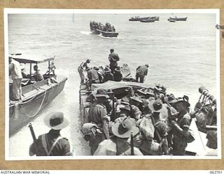 KANOMI BEACH, NEW GUINEA. 1944-01-05. TROOPS OF THE 2/23RD AUSTRALIAN INFANTRY BATTALION, 27TH AUSTRALIAN INFANTRY BRIGADE, 9TH AUSTRALIAN DIVISION GOING ABOARD BARGES FOR THEIR TRIP UP THE COAST ..