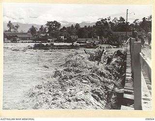 LAE, NEW GUINEA. 1945-10-14. DEBRIS FROM THE BUTIBUM RIVER PILED AGAINST THE BRIDGE BY FLOOD WATERS. FOLLOWING HEAVY RAINS THE BUTIBUM RIVER OVERFLOWED ITS BANKS, FLOODED THE ROAD AND ADJOINING ..