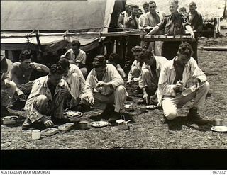 Ramu Valley, New Guinea. 1943-12-25. Patients of the 2/6th Australian Field Ambulance enjoying their picnic style Christmas dinner outdoors. Identified personnel are: SX8365 Sergeant F. Watts (2); ..