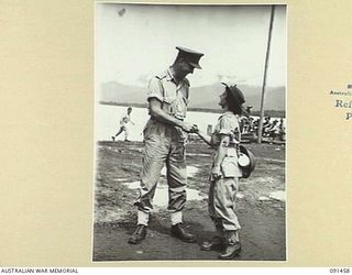 LAE, NEW GUINEA, 1945-05-07. LIEUTENANT. C.M.F. ALDRED (1) OF BINGARA, NSW, GREETING PRIVATE M. ARMSTRONG (2) ALSO OF BINGARA, ON THE BEACH AT MILFORD HAVEN. PTE ARMSTRONG, JUST DISEMBARKED FROM MV ..