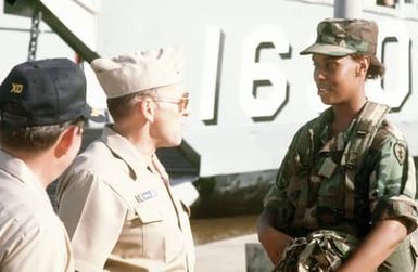 RADM William Retz, commander, Naval Base, Pearl Harbor, speaks with a soldier as CAPT Robert Annis, executive officer of the amphibious assault ship USS BELLEAU WOOD (LHA-3), stands by during the unloading of supplies from the BELLEAU WOOD. Members of the Joint Task Force Garden Isle are taking part in the supply delivery to assist residents of Kauai and surrounding areas in the aftermath of Hurricane Iniki