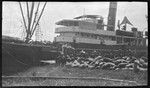 Men loading sacks of copra onto ship