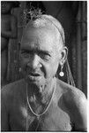 An elderly Kwaio woman, her woven 'purse' over her head, wearing shell earrings