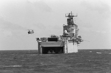 A Marine Corps CH-46E Sea Knight helicopter approaches the flight deck of the amphibious assault ship USS SAIPAN (LHA-2) as the ship sits offshore near Vieques, Puerto Rico, during Fleet Ex 1-90. The stern gate of the SAIPAN is open for landing craft operations