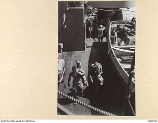 WEWAK HARBOUR, NEW GUINEA. 1945-11-25. NAVAL PERSONNEL ASSISTING TROOPS OF 6 DIVISION WITH THEIR GEAR AS THEY MOVE ALONG THE QUARTER DECK OF HMAS SHROPSHIRE. THE TROOPS ARE RETURNING TO AUSTRALIA ..