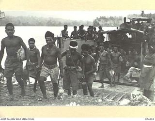 MALAMAL, NEW GUINEA. 1944-07-13. NEW GUINEA NATIVES COMING ASHORE FROM AN LCM (LANDING CRAFT MECHANISED) AT THE AUSTRALIAN NEW GUINEA ADMINISTRATIVE UNIT NATIVE LABOUR COMPOUND AFTER THEIR DAYS ..